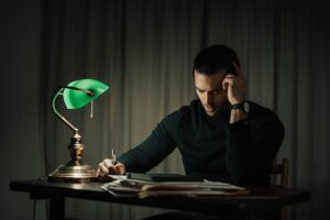 thoughtful man writing on paper at table