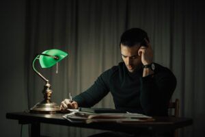 thoughtful man writing on paper at table